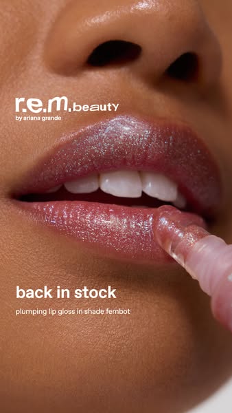 This ad showcases a close-up of a woman's face as she applies r.e.m. beauty's plumping lip gloss in the shade Fe