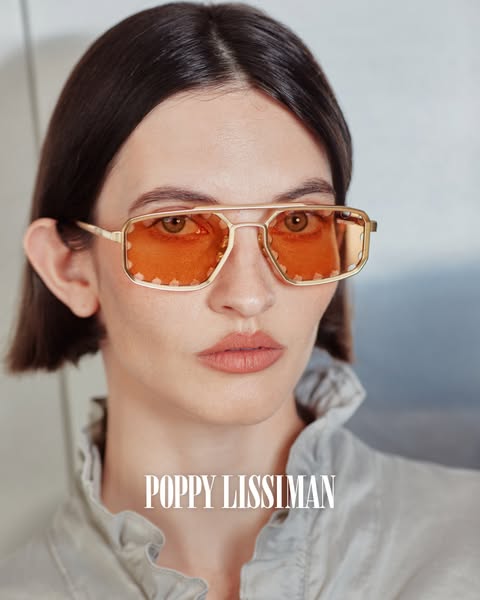 A close up shot of a person wearing orange tinted Poppy Lissiman sunglasses.