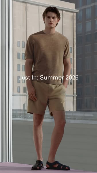 An image showcasing a man wearing a beige-colored short-sleeve top and beige shorts, paired with sandals, against a back