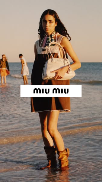 The ad features a model standing on a beach with a Miu Miu handbag and wearing Miu Miu clothing. There are other models 