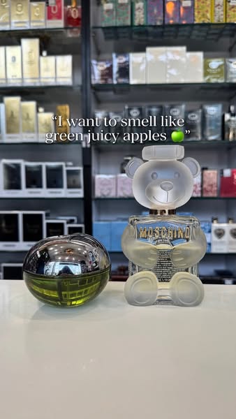 This ad showcases two distinct perfume bottles, one shaped like a teddy bear and the other like an apple, appealing to t