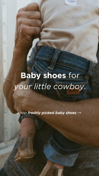 This ad showcases a pair of baby cowboy boots. The image focuses on the baby being held by an adult, emphasizing the boo