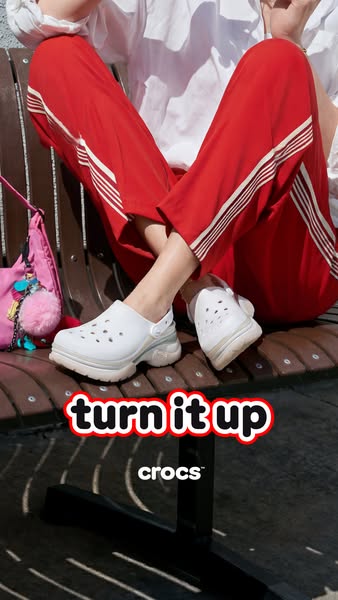 This ad features a single image of Crocs Crush Clogs. The focal point is the shoes, with a person seated above them on a