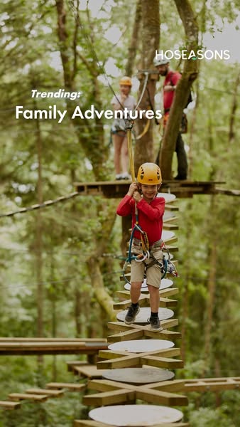 An image ad for Hoseasons promoting family adventure holidays, showing a family enjoying a treetop adventure course.