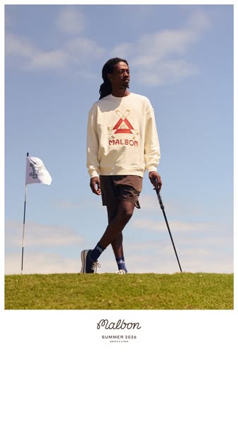 This ad for Malbon golf apparel features a Black man standing on a grassy green hill in front of a blue sky wearing a cr