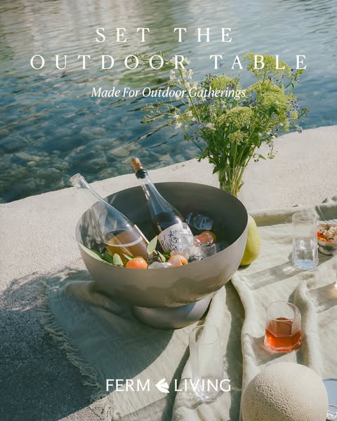 This Ferm Living ad presents a serene outdoor gathering scene, highlighting the brand's table setting products. It e