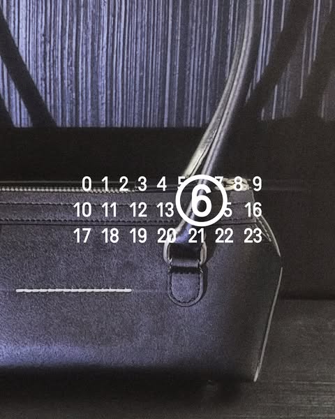 This ad is of a black leather handbag with a row of stitching across the front and the brand's signature numbers cir