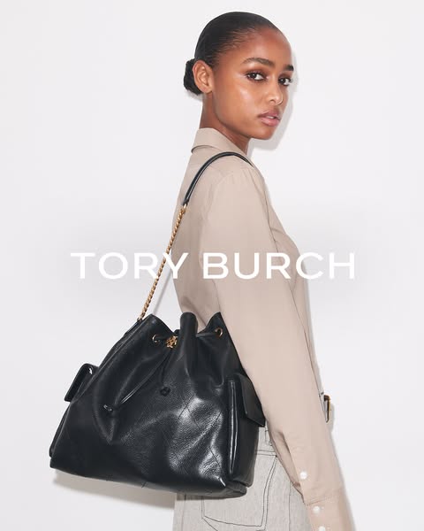 This ad showcases a woman modeling a black Tory Burch handbag, highlighting its design and style.