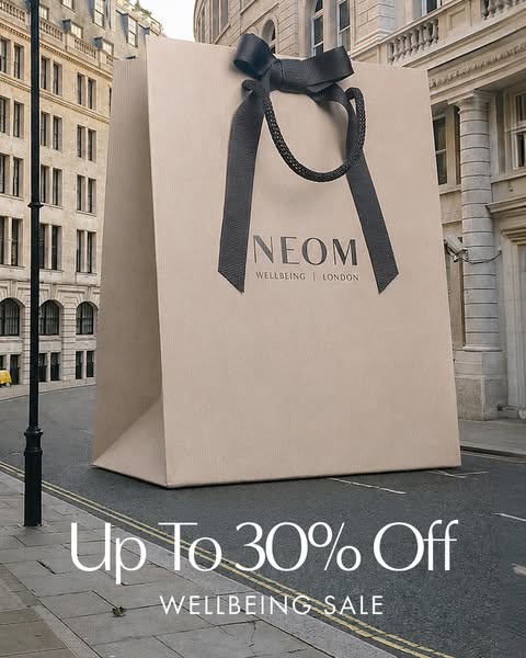 This image ad promotes NEOM's Wellbeing sale, offering up to 30% off. It features a large NEOM shopping bag on a Lon