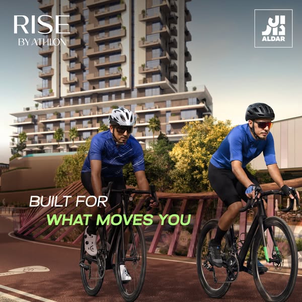 This image ad for RISE by Athlon, developed by ALDAR, features two cyclists riding on a path with the residential buildi