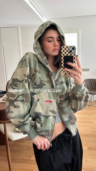 This ad features a young woman taking a selfie while wearing a camo zip-up hoodie.