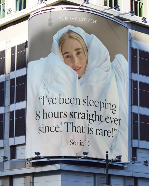 This ad features an image of a fair-skinned woman wrapped in a white comforter from Sunday Citizen. She is smiling sligh