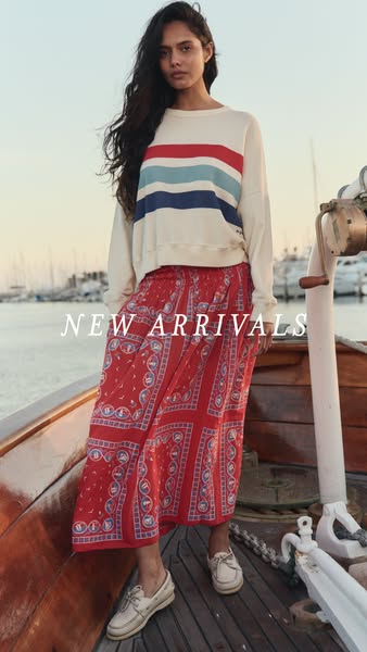 An advertisement for new arrivals of women's clothing. The image shows a female model wearing a long-sleeved top and