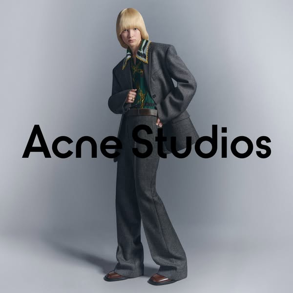 This ad features a person wearing a grey suit with the brand name Acne Studios displayed in the center.