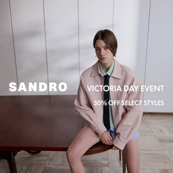 This ad for Sandro features a model wearing a pastel pink jacket, light blue shirt, and blue shorts with a black tie. Th