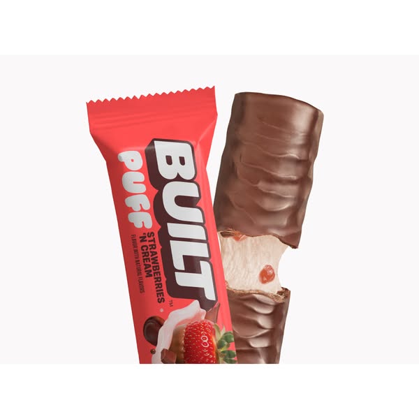 This ad features a close-up shot of a Built Puff protein bar in Strawberries 'N Cream flavor. The ad highlights the 