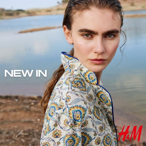 This H&M ad features a woman in front of a body of water, wearing a patterned shirt.