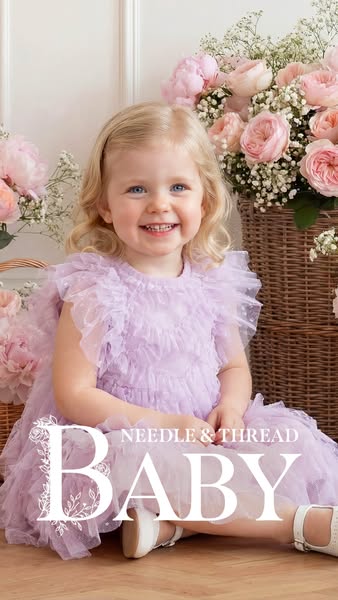 A photo of a young girl modeling a Needle & Thread dress. The dress is a light purple color, and the background feat