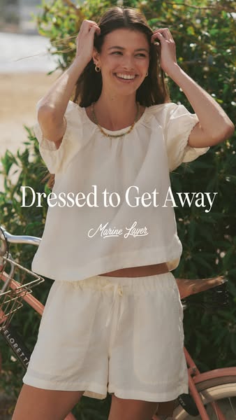 This ad features a woman wearing a matching linen top and shorts from Marine Layer. She is standing outside next to a bi