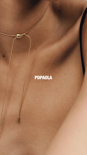 This ad features a close-up shot of a woman's chest and neck, highlighting a gold necklace from the brand PDPAOLA. T