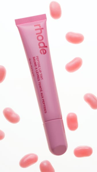 This ad features a tube of Rhode Peptide Lip Tint surrounded by pink jelly bean candies. The ad focuses on the product i