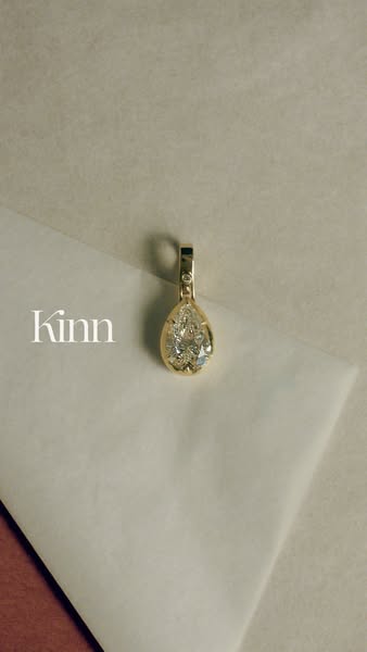 This ad showcases a gold and diamond pendant from Kinn, highlighting its design and craftsmanship.