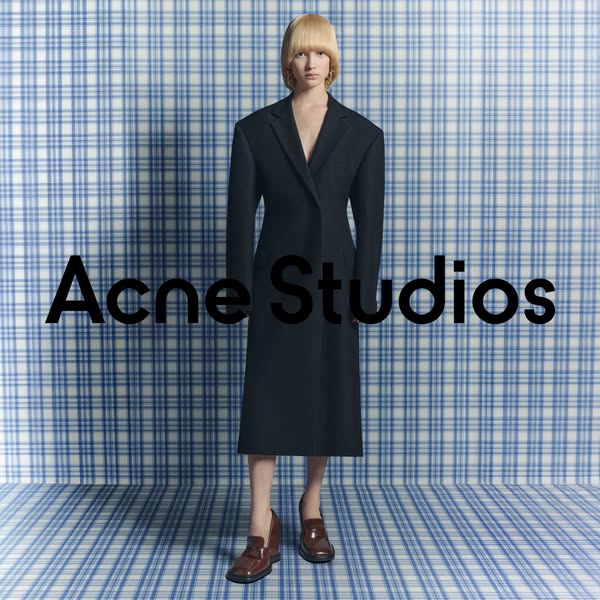 This ad features a model wearing a black Acne Studios coat and brown loafers against a blue and white plaid background. 