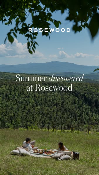 This image ad showcases Rosewood hotels by displaying a couple enjoying a picnic in a grassy field with rolling hills in