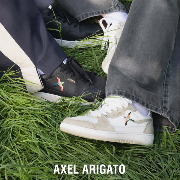 This ad features multiple individuals sporting Axel Arigato sneakers while sitting on grass. The brand name is featured 