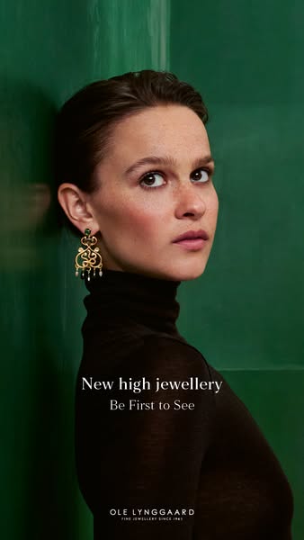 This image ad for Ole Lynggaard features a woman with natural makeup wearing one of the brand's gold statement earri