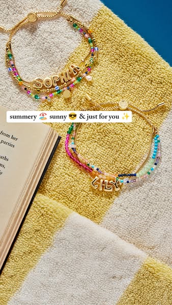 Close up of two beaded bracelets laid across a striped towel, one bracelet says Sophia and the other Lily. The image is