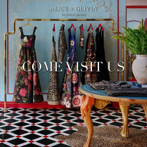 Image ad for Alice + Olivia featuring several dresses on a clothing rack and a table with purses on it.
