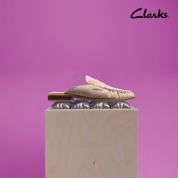 This ad showcases a beige-colored Clarks mule on a wooden cube, which is sitting on a bed of silver, springy coils. The 