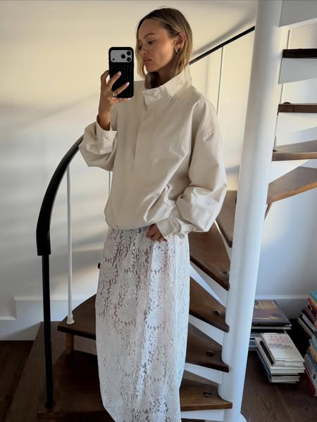 This ad features a woman taking a mirror selfie of her OOTD. She is wearing a casual light jacket with a high collar, an