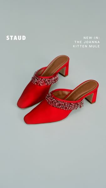 This ad showcases the new Joanna Kitten Mule from the brand STAUD. The ad features a pair of the red mules on a light bl