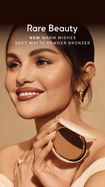 An ad for Rare Beauty's new Warm Wishes Soft Matte Powder Bronzer featuring a close up of Selena Gomez holding the b