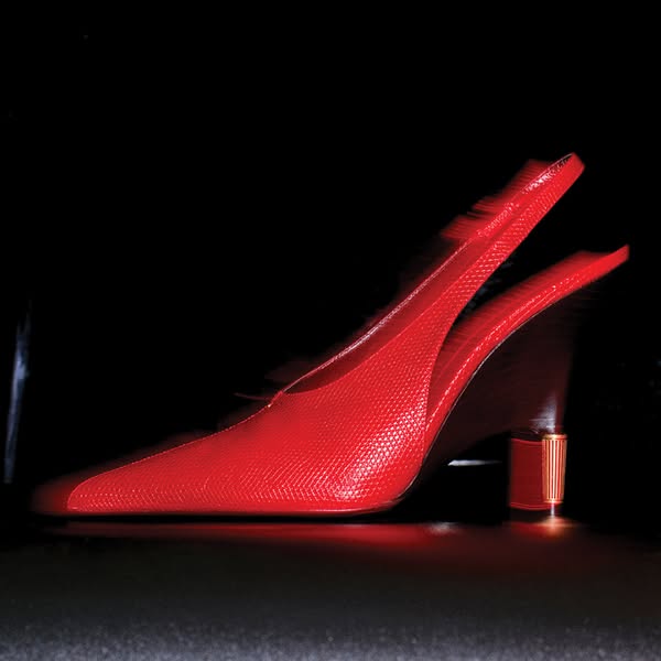 This ad features a single red high heel shoe against a black background, shown in a hero shot format. The creative is in