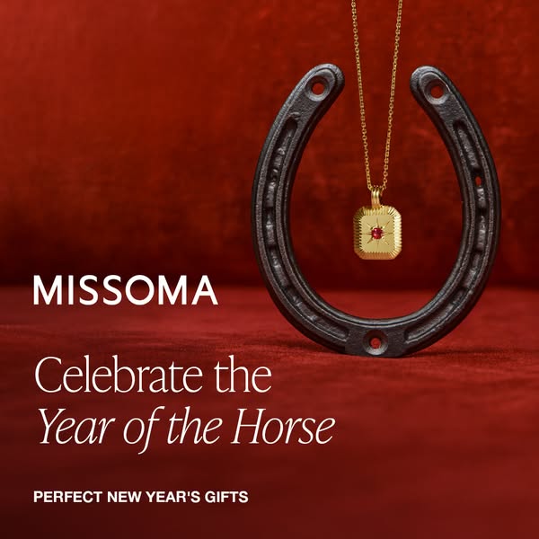 This ad for Missoma jewelry highlights a gold pendant necklace with a red stone, set against a red background with a hor