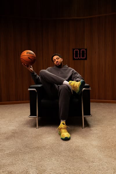 This ad features a man in casualwear seated in a chair, holding a basketball and wearing Puma shoes. The staging suggest