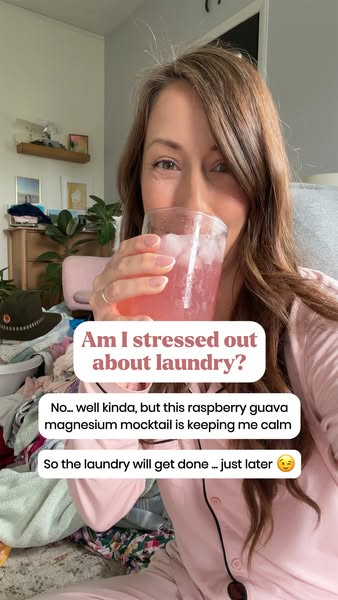 This image ad features a woman in pink pajamas holding a raspberry guava magnesium mocktail in front of a pile of laundr