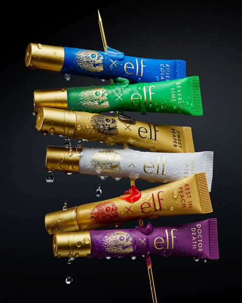 This ad features a stack of flavored lip gloss tubes suspended in the air by needles. Water droplets surround the tubes.