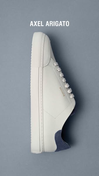 This image ad showcases a light beige Axel Arigato sneaker on a gray background. The text at the top displays the brand 