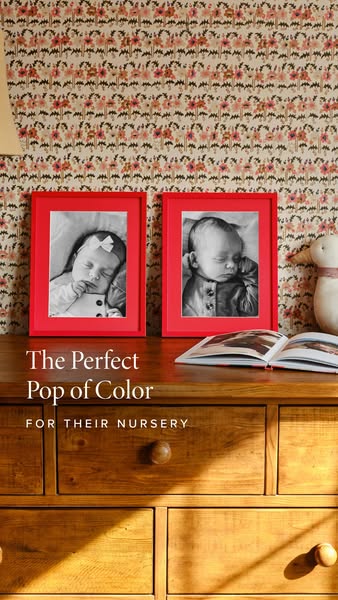 An advertisement for framed pictures features two black and white photos of babies in bright red frames on top of a wood