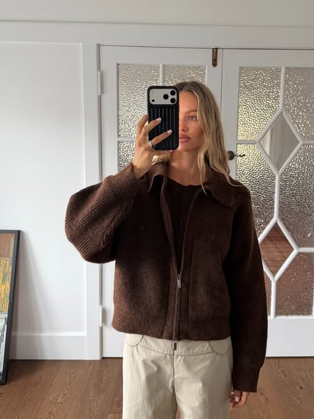 The image is of a woman taking a selfie in the mirror to show off her new brown knit jacket and pants. The ad seems to b