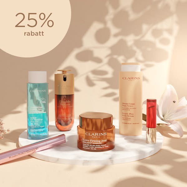 The ad features a range of Clarins skincare and makeup products displayed on a round marble platform. The ad highlights 