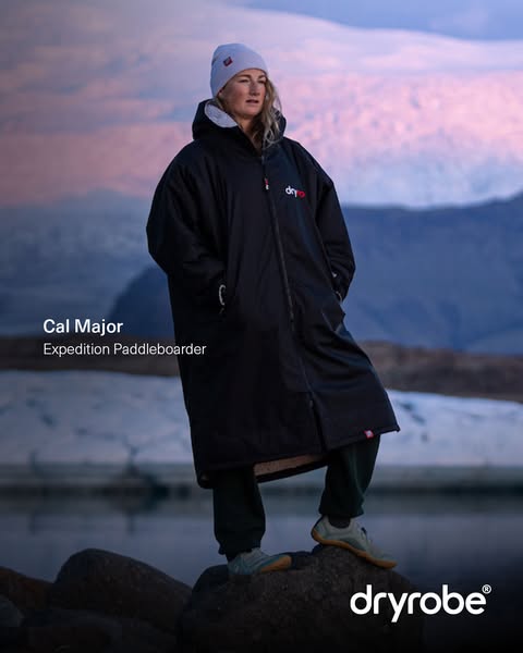 This ad features an image of Cal Major, an expedition paddleboarder, wearing a black dryrobe Advance Long Sleeve. The ad
