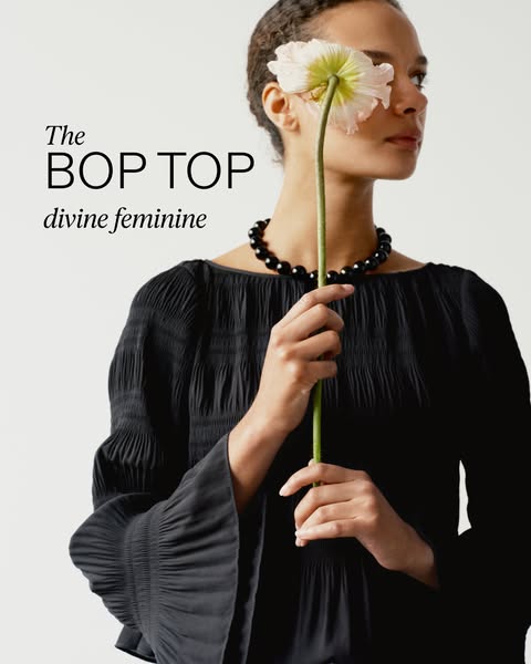 This image ad features a Black female presenting as feminine, holding a flower in front of her face while wearing a blac