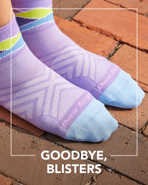 This image promotes Darn Tough socks as a solution to blisters, using a close up shot of the product on a brick surface,