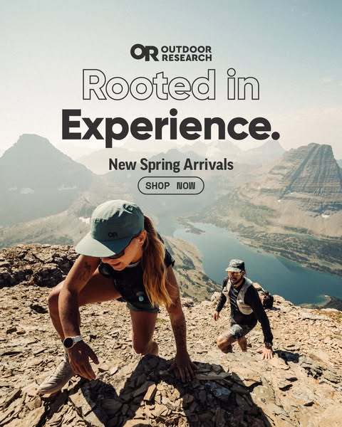 This image ad for Outdoor Research features two hikers climbing a rocky terrain with a lake and mountains in the backgro
