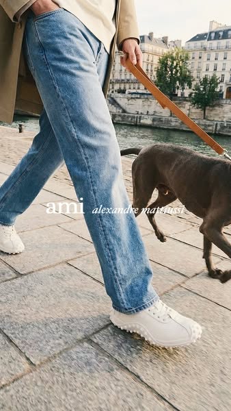This ad shows a brand called ami promoting their new shoes. A person walks a dog by the river while wearing the shoes. T